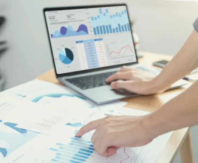 Person analyzing data charts on laptop and documents.